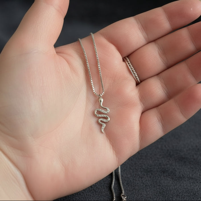 hand holding a snake necklace with 2 rings